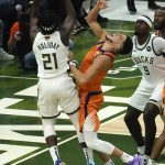 Milwaukee Bucks guard Jrue Holiday (21) shoots over Phoenix Suns guard Devin Booker during the first half of Game 4 of basketball's NBA Finals in Milwaukee, Wednesday, July 14, 2021. (AP Photo/Paul Sancya)