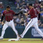 Arizona Diamondbacks third baseman Eduardo Escobar (5) slaps gloves with shortstop Nick Ahmed (13) after Escobar made a diving play on a grounder hit by Pittsburgh Pirates' John Nogowski during the third inning of a baseball game, Wednesday, July 21, 2021, in Phoenix. (AP Photo/Ross D. Franklin)