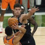 Milwaukee Bucks center Brook Lopez, facing, pressures Phoenix Suns guard Devin Booker during the first half of Game 6 of basketball's NBA Finals in Milwaukee, Tuesday, July 20, 2021. (AP Photo/Paul Sancya)