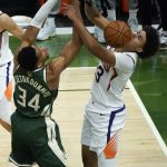 Milwaukee Bucks forward Giannis Antetokounmpo (34) and Phoenix Suns forward Cameron Johnson (23) battle for a loose ball during the second half of Game 3 of basketball's NBA Finals in Milwaukee, Sunday, July 11, 2021. (AP Photo/Paul Sancya)