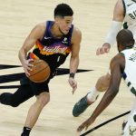 Phoenix Suns guard Devin Booker (1) drives as Milwaukee Bucks forward Khris Middleton (22) defends during the first half of game 1 of basketball's NBA Finals, Tuesday, July 6, 2021, in Phoenix. (AP Photo/Matt York, Pool)