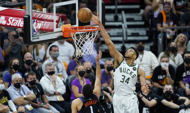 Phoenix Suns guard Devin Booker (1) scores as Milwaukee Bucks forward Giannis Antetokounmpo (34) is...