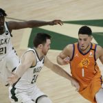 Phoenix Suns guard Devin Booker (1) drives past Milwaukee Bucks guard Pat Connaughton (24) and guard Jrue Holiday (21) during the first half of Game 4 of basketball's NBA Finals Wednesday, July 14, 2021, in Milwaukee. (AP Photo/Aaron Gash)