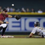 Arizona Diamondbacks second baseman Josh Rojas, left, is unable to make field the throw as Pittsburgh Pirates' Adam Frazier, right, advances to second base on a fly out during the third inning of a baseball game, Wednesday, July 21, 2021, in Phoenix. (AP Photo/Ross D. Franklin)