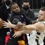 Milwaukee Bucks guard Pat Connaughton, right, is defended by Phoenix Suns forward Jae Crowder during the first half of Game 5 of basketball's NBA Finals, Saturday, July 17, 2021, in Phoenix. (AP Photo/Matt York)