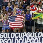 
              Fans wave American and Jamaican flags during team warmups before a 2021 CONCACAF Gold Cup quarterfinals soccer match, Sunday, July 25, 2021, in Arlington, Texas. (AP Photo/Brandon Wade)
            