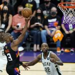 Phoenix Suns guard Chris Paul (3) scores as Milwaukee Bucks forward Khris Middleton (22) and Bucks guard Jrue Holiday, left, look on during the second half of Game 1 of basketball's NBA Finals, Tuesday, July 6, 2021, in Phoenix. (AP Photo/Ross D. Franklin)