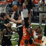 Milwaukee Bucks center Brook Lopez (11) goes to the basket against Phoenix Suns center Deandre Ayton (22) during the first half of Game 6 of basketball's NBA Finals in Milwaukee, Tuesday, July 20, 2021. (AP Photo/Paul Sancya)