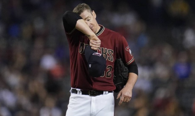 Arizona Diamondbacks relief pitcher Ryan Buchter wipes sweat from his face after giving up a two-ru...
