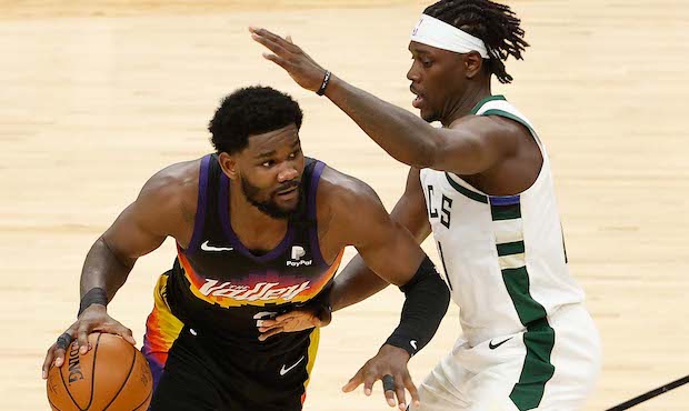 Deandre Ayton #22 of the Phoenix Suns handles the ball against Jrue Holiday #21 of the Milwaukee Bu...
