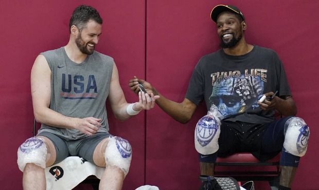 Kevin Love, left, and Kevin Durant laugh while passing a cell phone after practice for USA Basketba...