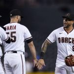 Arizona Diamondbacks left fielder David Peralta (6) celebrates with relief pitcher Jake Faria, middle, and catcher Carson Kelly after the team's baseball game against the San Diego Padres, Thursday, Aug. 12, 2021, in Phoenix. The Diamondbacks won 12-3. (AP Photo/Ross D. Franklin)