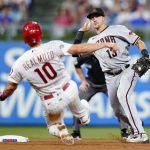 Arizona Diamondbacks shortstop Nick Ahmed, right, throws to first base after forcing out Philadelphia Phillies' J.T. Realmuto at second on a double play hit into by Didi Gregorius during the seventh inning of a baseball game, Friday, Aug. 27, 2021, in Philadelphia. (AP Photo/Matt Slocum)