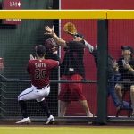 Arizona Diamondbacks right fielder Pavin Smith runs out of room as fans reach for a two-run home run hit by San Diego Padres' Jake Cronenworth during the fifth inning of a baseball game, Sunday, Aug. 15, 2021, in Phoenix. (AP Photo/Ross D. Franklin)