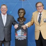 Tom Flores, a member of the Pro Football Hall of Fame Class of 2021, right, and his presenter Las Vegas Raiders owner Mark Davis pose with the bust during the induction ceremony at the Pro Football Hall of Fame, Sunday, Aug. 8, 2021, in Canton, Ohio. (AP Photo/Ron Schwane, Pool)