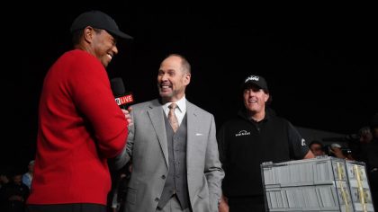 Phil Mickelson celebrates with the winnings after defeating Tiger Woods as Ernie Johnson looks on d...