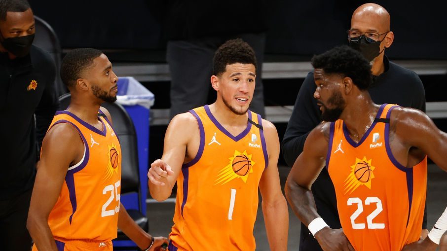 Devin Booker #1 of the Phoenix Suns talks with Mikal Bridges #25 and Deandre Ayton #22 during the f...