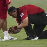 Southern Utah head coach Demario Warren ties the shoe of one of his players during the first half of an NCAA college football game against the Arizona State, Thursday, Sept. 2, 2021, in Tempe, Ariz. (AP Photo/Matt York)