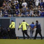 Two fans who made their way on to the field are taken in to custody by security personnel during a baseball game between the Arizona Diamondbacks and the Los Angeles Dodgers Wednesday, Sept. 15, 2021, in Los Angeles. (AP Photo/Ashley Landis)