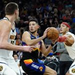 Phoenix Suns guard Devin Booker (1) looks to pass as Denver Nuggets forward Aaron Gordon, right, defends during the second half of an NBA basketball game, Wednesday, Oct. 20, 2021, in Phoenix. (AP Photo/Matt York)