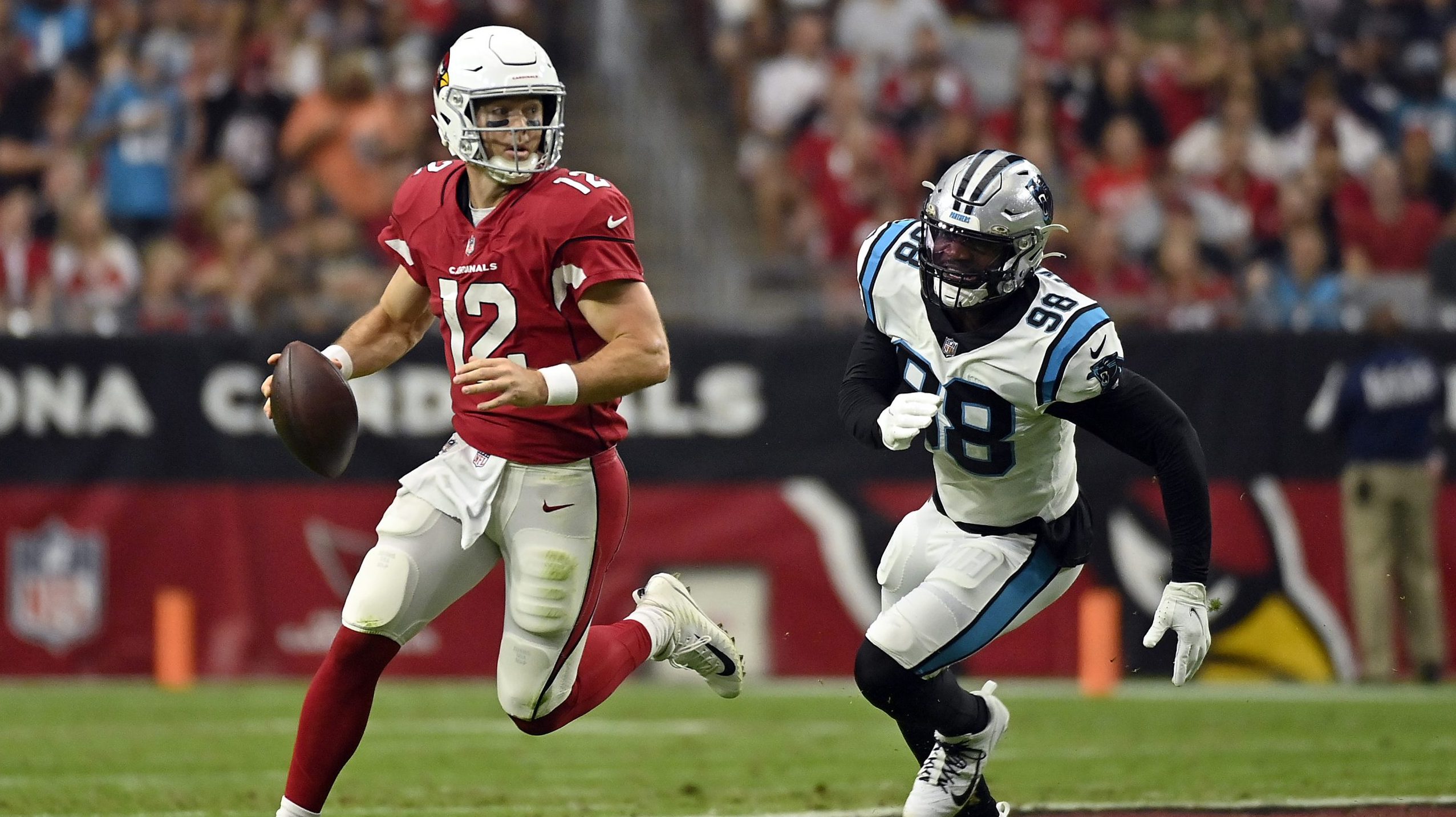 Colt McCoy #12 of the Arizona Cardinals scrambles out of the pocket away from Marquis Haynes Sr. #9...