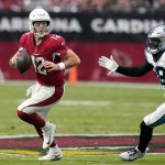 Arizona Cardinals quarterback Colt McCoy (12) scrambles away from Carolina Panthers defensive end Marquis Haynes, right, during the first half of an NFL football game Sunday, Nov. 14, 2021, in Glendale, Ariz. (AP Photo/Darryl Webb)