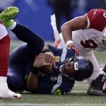 Seattle Seahawks quarterback Russell Wilson, bottom left, is sacked by Arizona Cardinals' Isaiah Simmons (9) during the first half of an NFL football game, Sunday, Nov. 21, 2021, in Seattle. (AP Photo/John Froschauer)