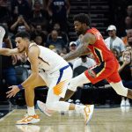 Phoenix Suns guard Devin Booker, left, saves the ball from going out of bounds as New Orleans Pelicans forward Naji Marshall (8) defends during the second half of an NBA basketball game Tuesday, Nov. 2, 2021, in Phoenix. The Suns won 112-100. (AP Photo/Ross D. Franklin)