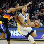 Golden State Warriors guard Stephen Curry (30) drives as Phoenix Suns forward Mikal Bridges defends during the first half of an NBA basketball game, Tuesday, Nov. 30, 2021, in Phoenix. (AP Photo/Matt York)