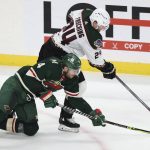 Arizona Coyotes right wing Hudson Fasching (24) and Minnesota Wild defenseman Jon Merrill (4) go after the puck during the third period of an NHL hockey game Tuesday, Nov. 30, 2021, in St. Paul, Minn. Minnesota won 5-2. (AP Photo/Stacy Bengs)