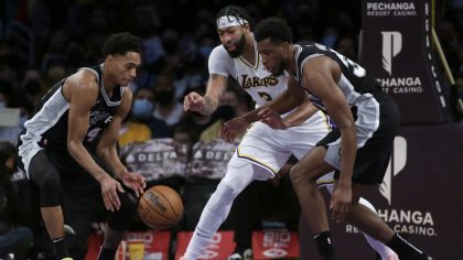 Los Angeles Lakers forward Anthony Davis, center, battles San Antonio Spurs guard Devin Vassell, le...
