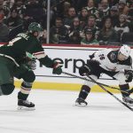 Arizona Coyotes left wing Antoine Roussel (26) handles the puck against Minnesota Wild defenseman Jon Merrill (4) during the second period of an NHL hockey game Tuesday, Nov. 30, 2021, in St. Paul, Minn. (AP Photo/Stacy Bengs)
