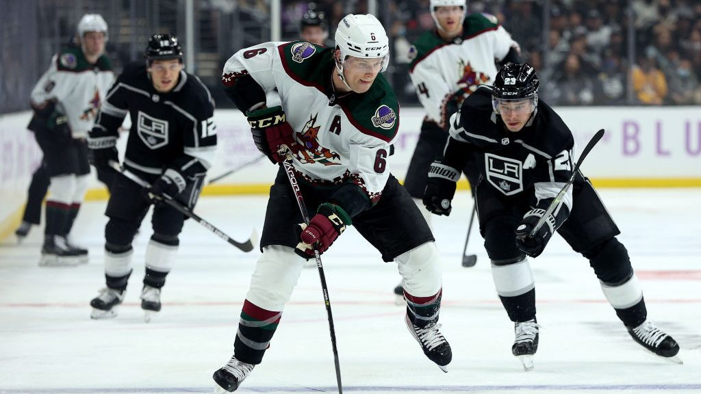 Jakob Chychrun #6 of the Arizona Coyotes skates with the puck as he is chased by Dustin Brown #23 o...