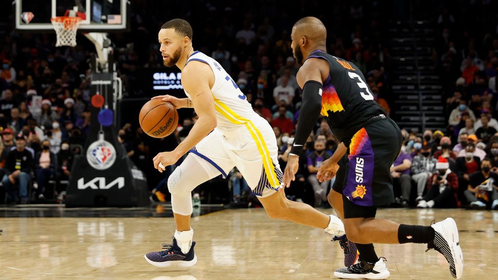 Stephen Curry #30 of the Golden State Warriors drives the ball past Chris Paul #3 of the Phoenix Su...