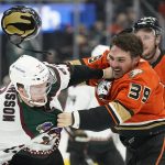 The helmet of Anaheim Ducks center Sam Carrick (39) flies off as he fights Arizona Coyotes left wing Johan Larsson (22) during the first period of an NHL hockey game in Anaheim, Calif., Friday, Dec. 17, 2021. (AP Photo/Ashley Landis)