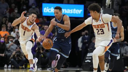 Memphis Grizzlies guard Desmond Bane (22) drives between Phoenix Suns guard Devin Booker (1) and fo...