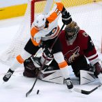 Philadelphia Flyers right wing Travis Konecny (11) redirects the puck as Arizona Coyotes goaltender Karel Vejmelka, right, readies to make the save during the first period of an NHL hockey game Saturday, Dec. 11, 2021, in Glendale, Ariz. (AP Photo/Ross D. Franklin)