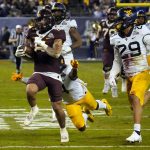 Minnesota running back Ky Thomas (8) runs away from West Virginia safety Alonzo Addae and safety Sean Mahone (29) during the first half of the Guaranteed Rate Bowl NCAA college football game Tuesday, Dec. 28, 2021, in Phoenix. (AP Photo/Rick Scuteri)