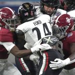 Cincinnati running back Jerome Ford (24) is tackled by Alabama's Kool-Aid McKinstry (1) and Christian Harris (8) during the first half of the Cotton Bowl NCAA College Football Playoff semifinal game, Friday, Dec. 31, 2021, in Arlington, Texas. (AP Photo/Jeffrey McWhorter)