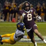 Minnesota running back Ky Thomas (8) gets away form West Virginia safety Saint McLeod during the second half of the Guaranteed Rate Bowl NCAA college football game Tuesday, Dec. 28, 2021, in Phoenix. Minnesota won 18-6. (AP Photo/Rick Scuteri)