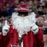An Arizona Cardinals fan, dressed as Santa Claus, cheers during the first half of an NFL football game against the Indianapolis Colts, Saturday, Dec. 25, 2021, in Glendale, Ariz. (AP Photo/Rick Scuteri)