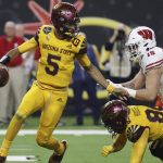 Arizona State quarterback Jayden Daniels (5) avoids a tackle by Wisconsin linebacker Nick Herbig (19) during the first half of the Las Vegas Bowl NCAA college football game Thursday, Dec. 30, 2021, in Las Vegas. (AP Photo/L.E. Baskow)