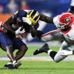 Michigan wide receiver Mike Sainristil is tackled by Georgia defensive back Christopher Smith, left, and linebacker Quay Walker during the first half of the Orange Bowl NCAA College Football Playoff semifinal game, Friday, Dec. 31, 2021, in Miami Gardens, Fla. (AP Photo/Jim Rassol)