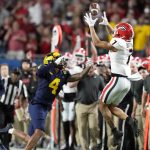 Georgia wide receiver Jermaine Burton catches a pass over Michigan defensive back Vincent Gray during the first half of the Orange Bowl NCAA College Football Playoff semifinal game, Friday, Dec. 31, 2021, in Miami Gardens, Fla. (AP Photo/Rebecca Blackwell)