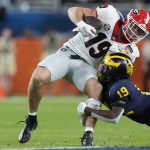 Georgia tight end Brock Bowers is tackled by Michigan defensive back Rod Moore during the first half of the Orange Bowl NCAA College Football Playoff semifinal game, Friday, Dec. 31, 2021, in Miami Gardens, Fla. (AP Photo/Rebecca Blackwell)