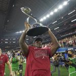 Alabama defensive lineman Byron Young carries the winner's trophy after the Cotton Bowl NCAA College Football Playoff semifinal game against Cincinnati, Friday, Dec. 31, 2021, in Arlington, Texas. Alabama won 27-6. (AP Photo/Jeffrey McWhorter)