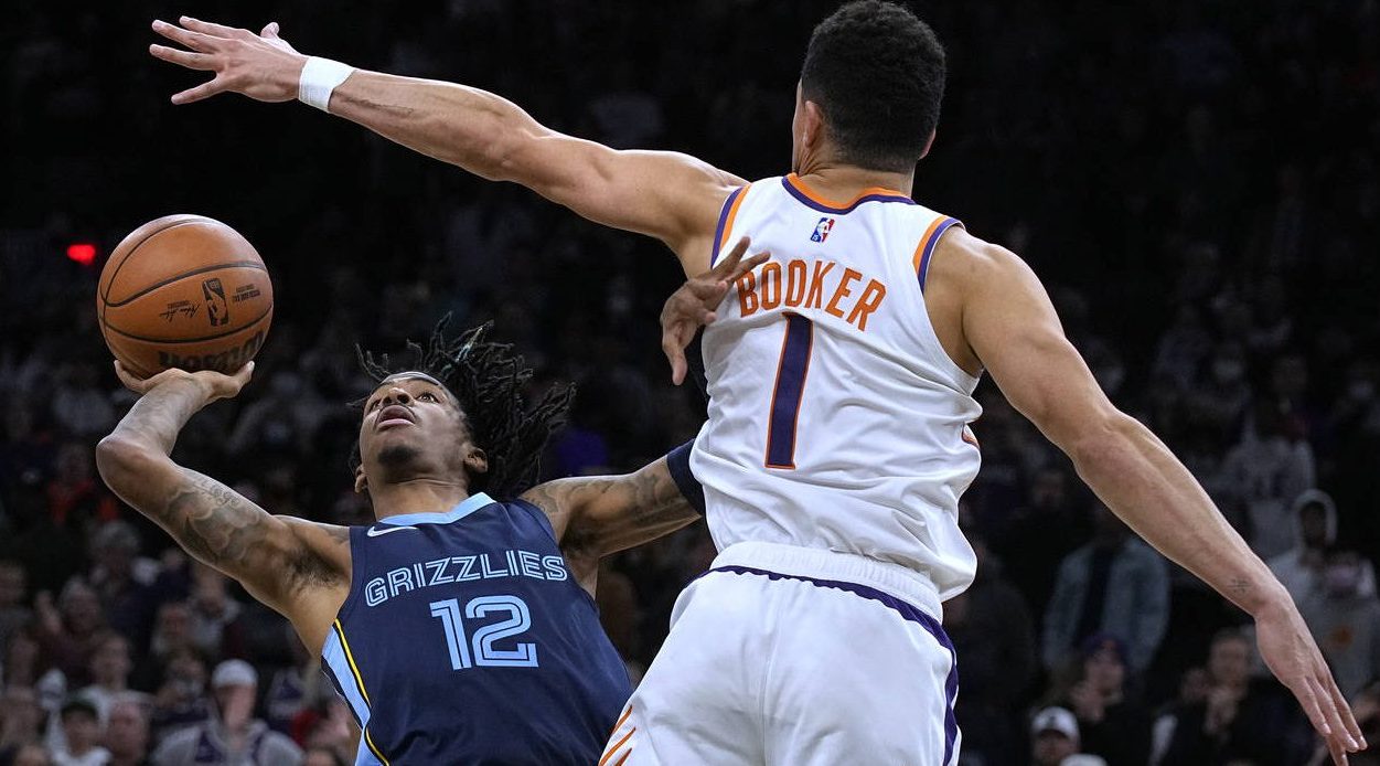 Memphis Grizzlies guard Ja Morant scores against Phoenix Suns guard Devin Booker (1) in the last se...