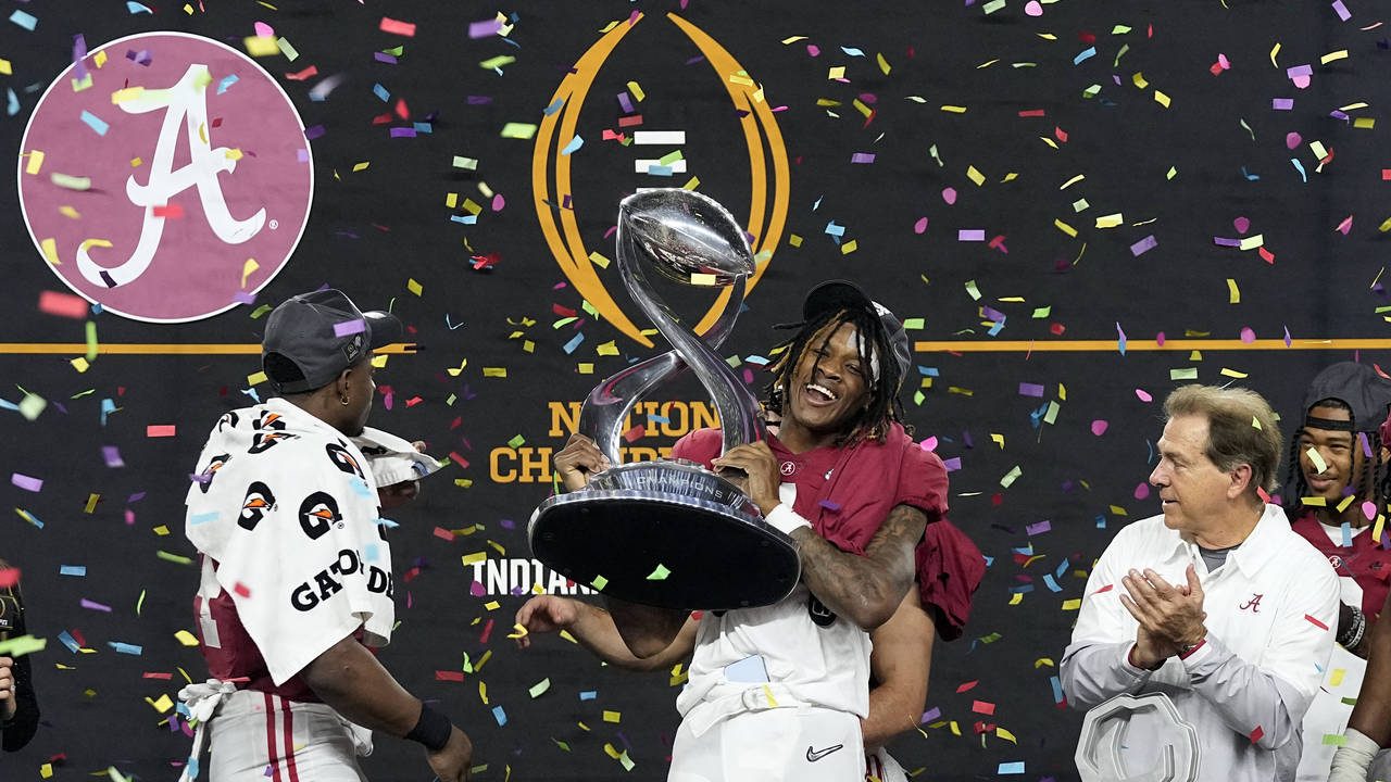 Alabama's Jameson Williams (1) holds up the winner's trophy as coach Nick Saban, right, and Brian R...