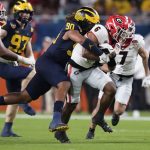 Georgia running back Kenny McIntosh is tackled by Michigan defensive end Mike Morris during the second half of the Orange Bowl NCAA College Football Playoff semifinal game, Friday, Dec. 31, 2021, in Miami Gardens, Fla. (AP Photo/Rebecca Blackwell)
