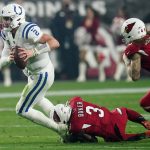 Indianapolis Colts quarterback Carson Wentz (2) is tripped up by Arizona Cardinals safety Budda Baker (3) during the second half of an NFL football game, Saturday, Dec. 25, 2021, in Glendale, Ariz. (AP Photo/Ross D. Franklin)
